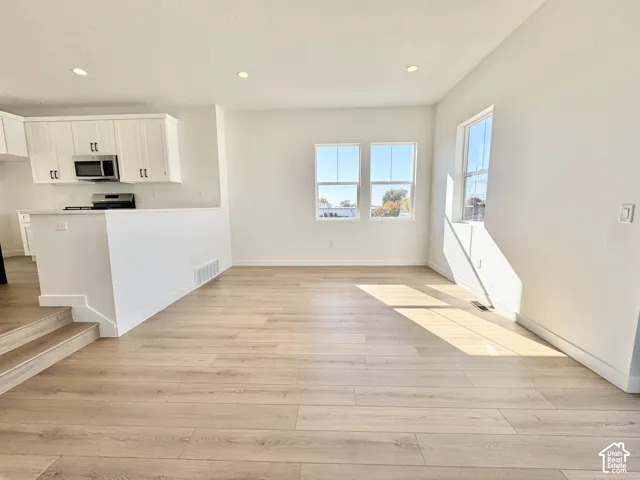 Open concept living area with wood-finish flooring, recessed lighting, and multiple windows