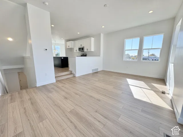 Open-concept living area with wood-finish flooring, recessed lighting, and two large windows