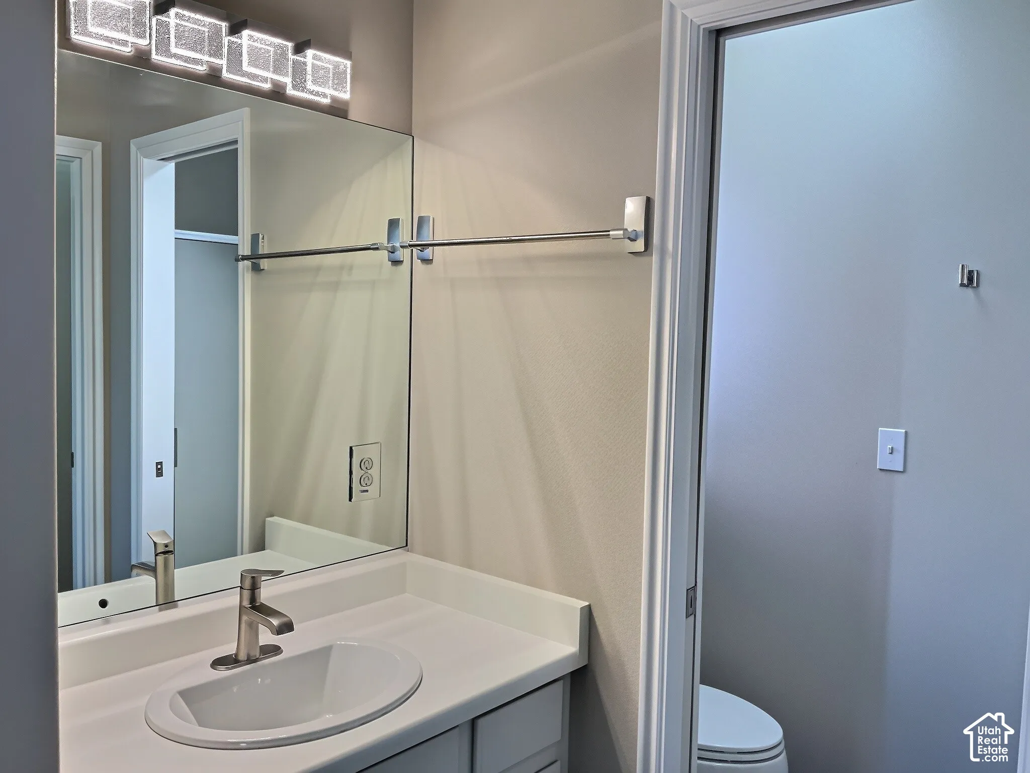 Vanity with a rectangular undermount sink, brushed nickel faucet, and a large mirror with integrated lighting