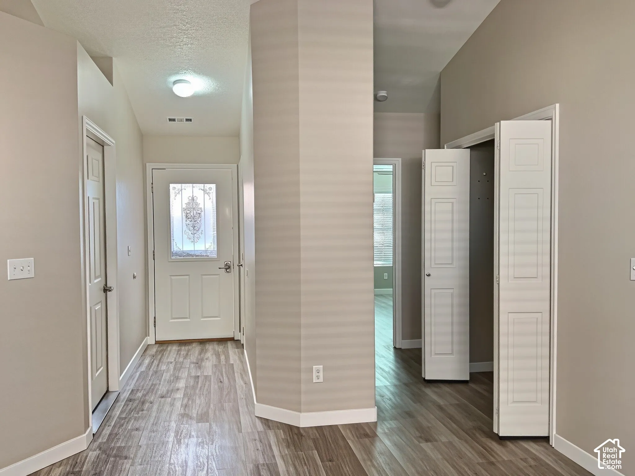 Entryway featuring wood-finish flooring, a decorative glass-paneled entry door, and vaulted ceilings