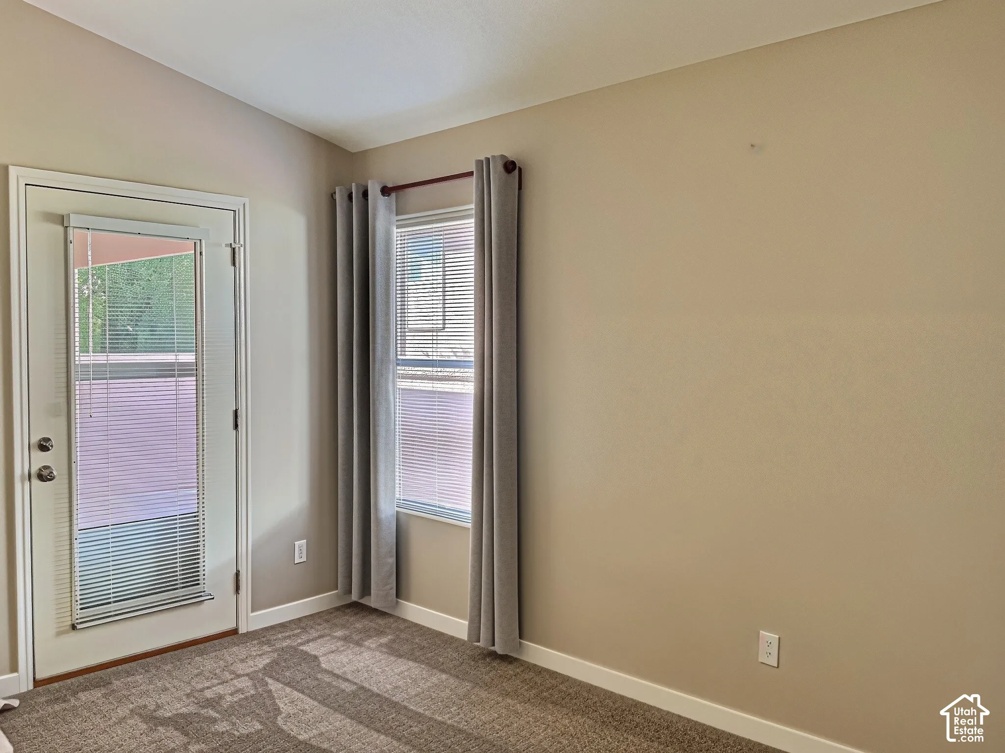 Vaulted ceiling, neutral wall paint, white trim, carpeted flooring, and a glass-paneled door