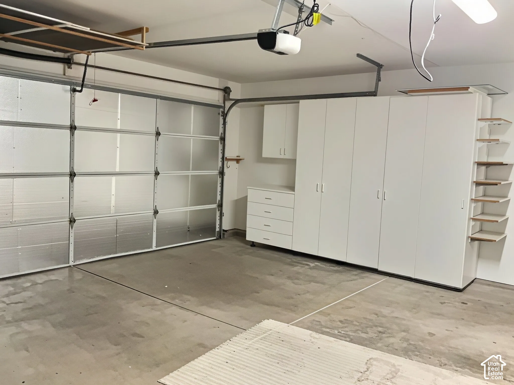 Garage featuring built-in white cabinetry, drawer storage, and open shelving