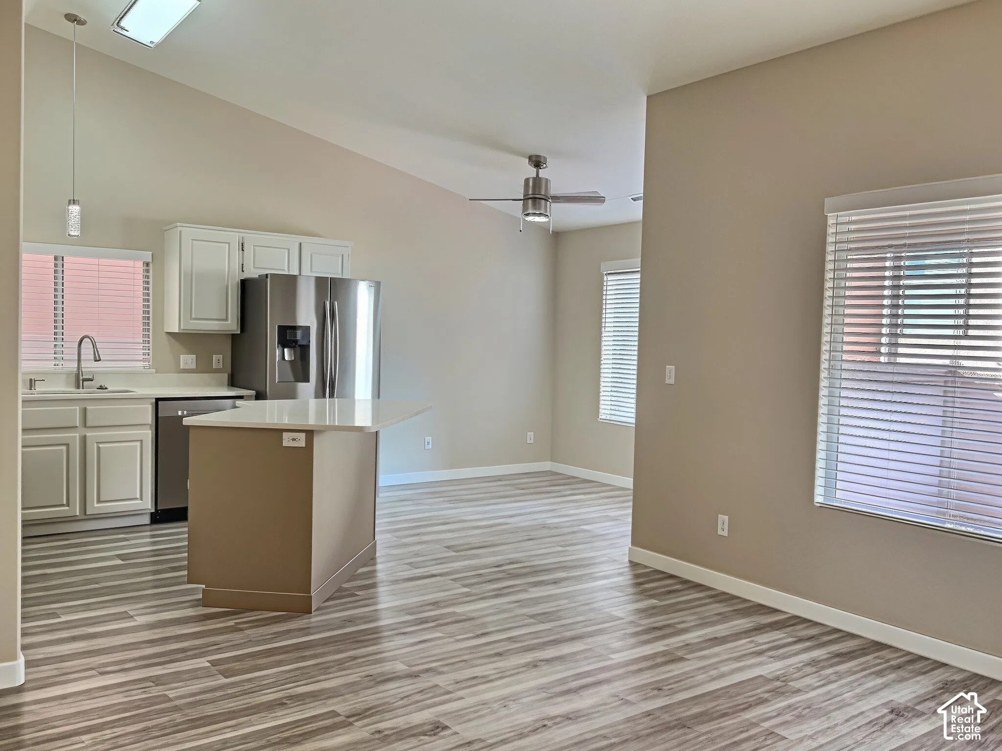 Kitchen featuring white cabinetry, stainless steel appliances, a center island with a light-toned countertop, and wood-finish flooring