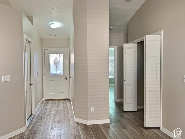Entryway featuring wood-finish flooring, a decorative glass-paneled entry door, and vaulted ceilings