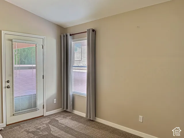 Vaulted ceiling, neutral wall paint, white trim, carpeted flooring, and a glass-paneled door