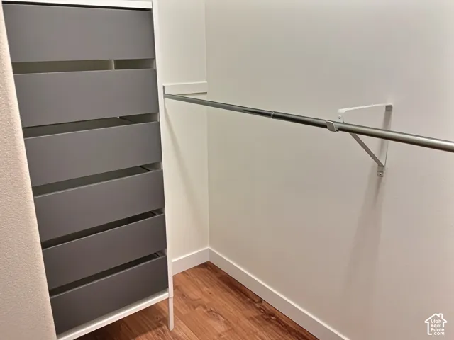 Built-in closet system with six drawers, mounted hanging rod, and wood-finish flooring