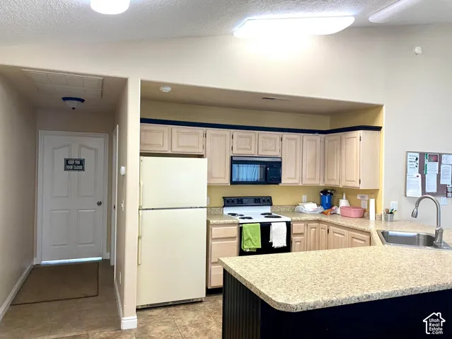Open-concept kitchen featuring light wood cabinetry, stainless steel appliances, a large quartz countertop island with contrasting base, and a tile backsplash