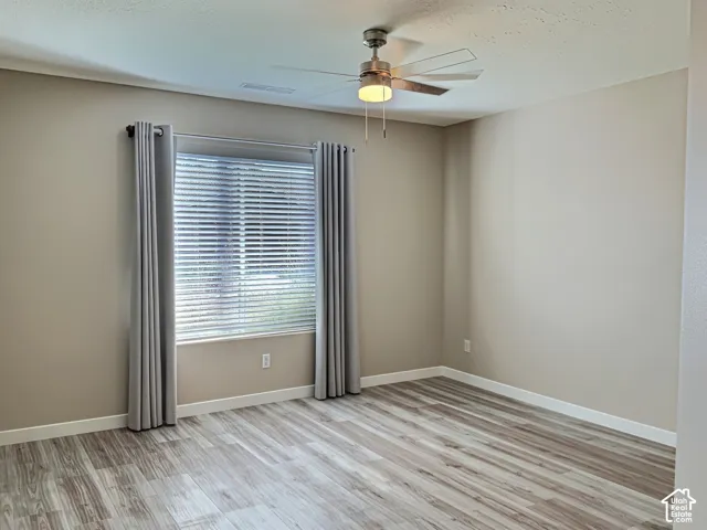 Room featuring wood-finish flooring, neutral paint palette, and a ceiling fan with integrated lighting