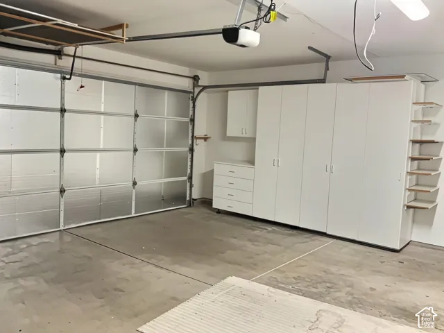 Garage featuring built-in white cabinetry, drawer storage, and open shelving