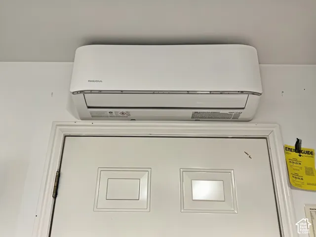 Wall-mounted air conditioning mini-split unit positioned above a paneled door in garage