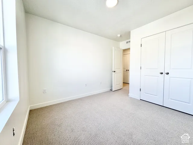 Light-colored carpeted flooring, white walls, and a window with white trim