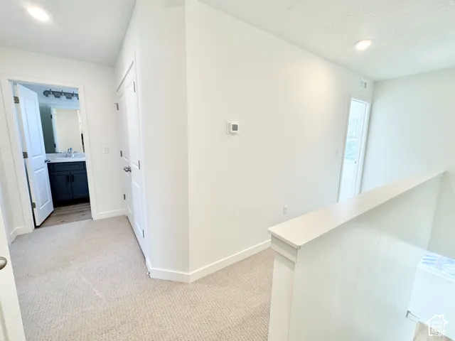 Light-toned carpeting with recessed lighting and white painted walls