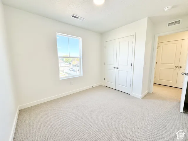 Recessed lighting, light-toned carpeting, white interior walls, white trim, and a double-door closet