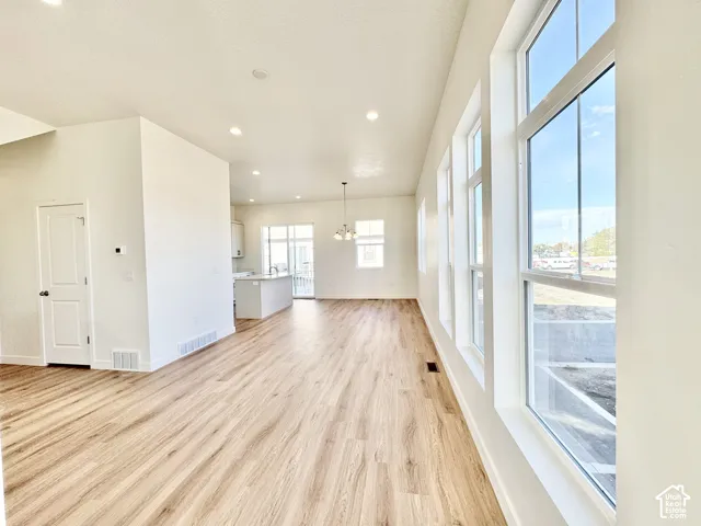 Wood-finish flooring throughout, recessed ceiling lighting, abundant natural light from multiple windows, and a white kitchen island