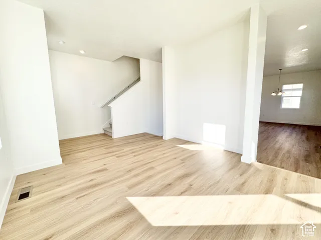 Open concept living area with wood-finish flooring, recessed lighting, and a staircase featuring a white railing