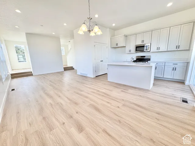 Open concept living area with wood-finish flooring, recessed lighting, and a modern kitchen