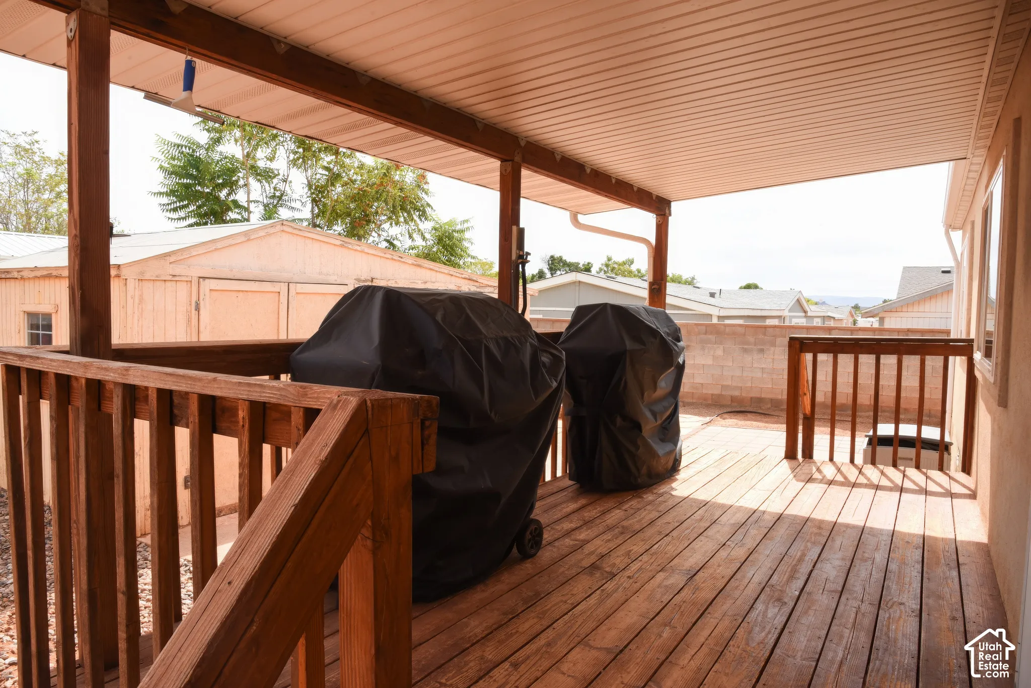 Covered wood-finish deck with wooden railings and partial privacy wall