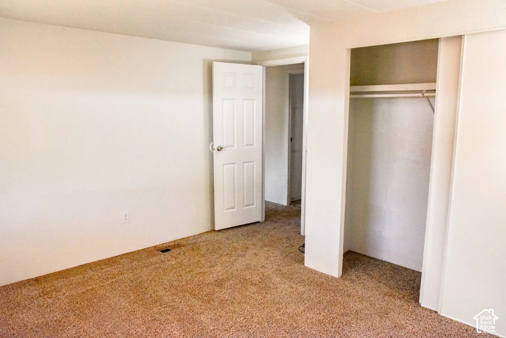 Wall-to-wall carpeting, neutral wall finishes, and a bi-fold closet with an integrated hanging rod
