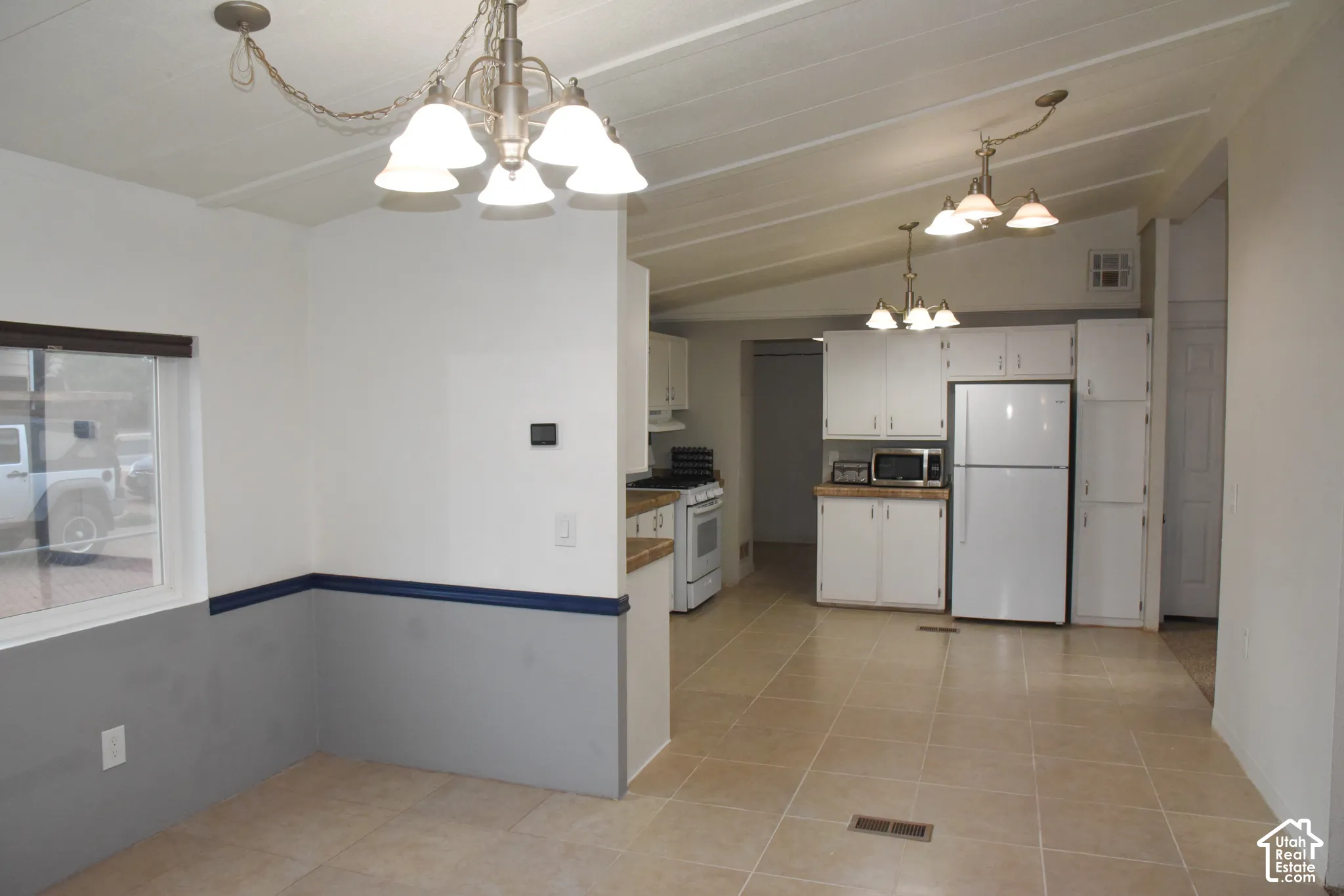 Dining room into kitchen Open-concept living space with tile flooring and vaulted ceilings