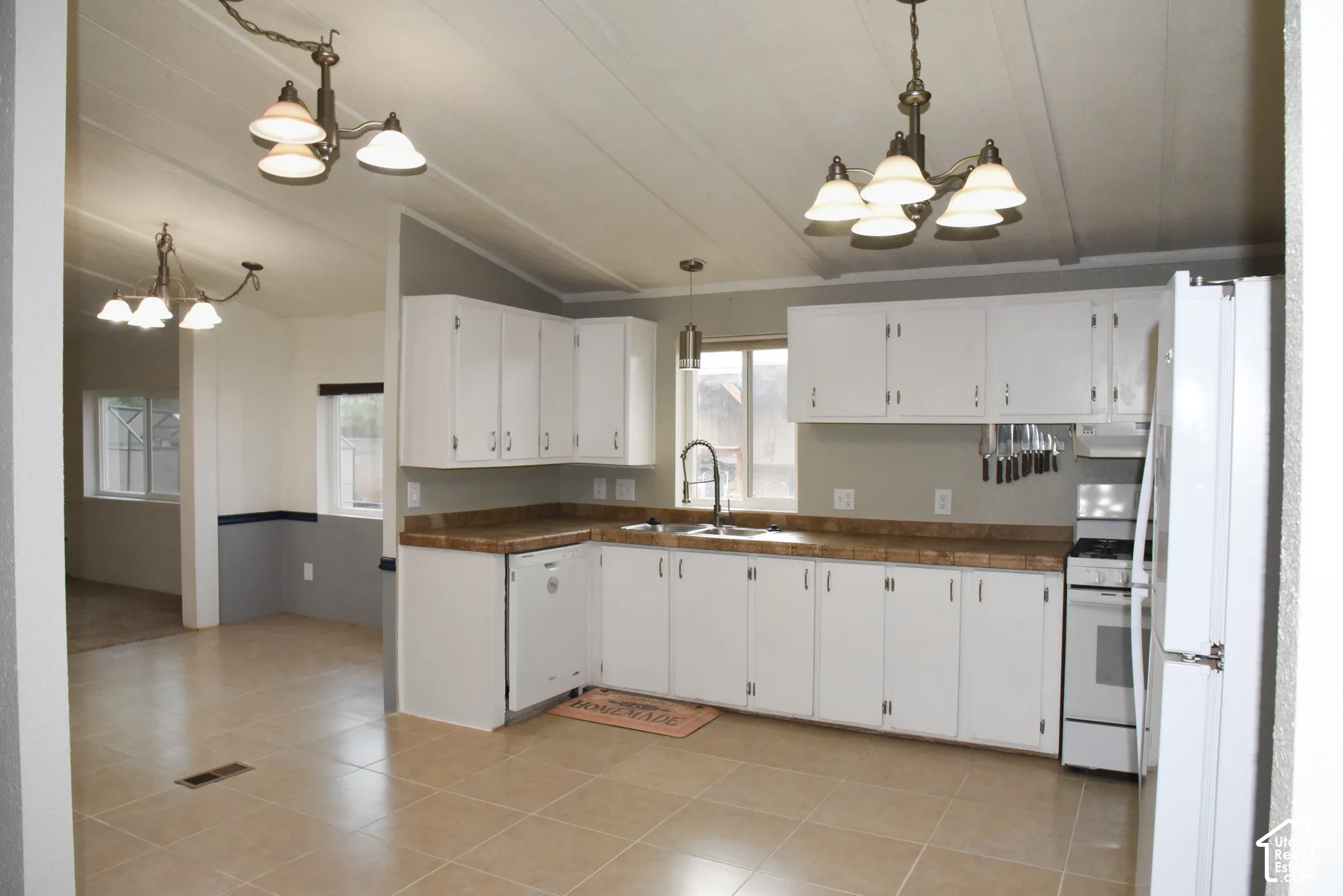 White cabinetry with silver-tone hardware, wood-finish countertops, and a white appliance package