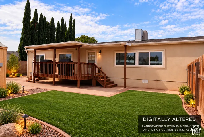 Expansive backyard featuring a covered deck with wood railing, paved patio area, and a privacy fence