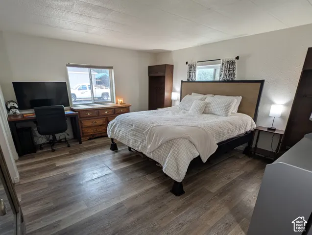 Wood-finish flooring throughout, multiple windows with blinds, a built-in wood-finish dresser, and ample wall space
