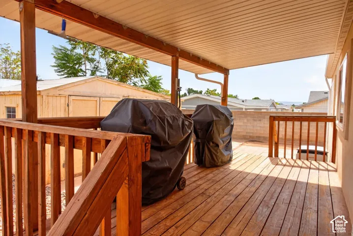 Elevated wood deck featuring a covered patio area, vertical wood railings, and stairs