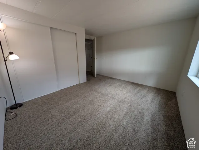 Wall-to-wall carpeting, sliding closet doors, and neutral wall tones