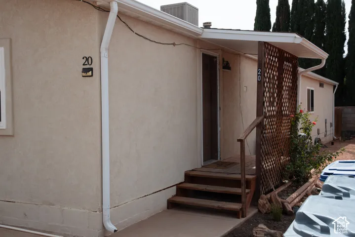 Stucco exterior with a covered entry, wood steps, and a decorative lattice privacy screen