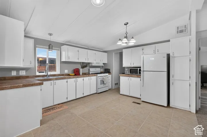 Kitchen featuring white cabinetry, tile countertops, tile flooring, and integrated lighting fixtures