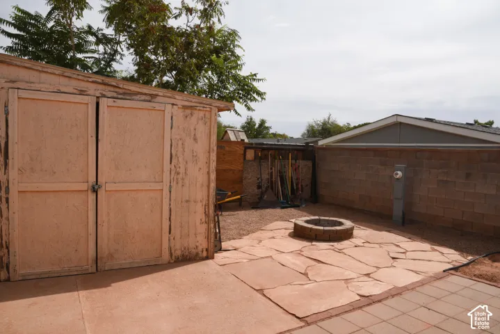 Backyard featuring a stone fire pit, flagstone patio, gravel landscaping, and a wood-panel storage shed
