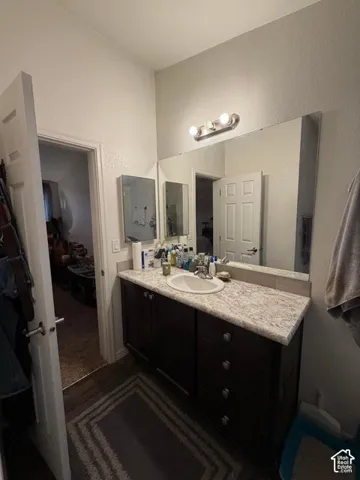 Dark wood-finish vanity with a single basin sink, patterned countertop, and an expansive wall-mounted mirror