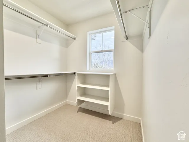 Walk-in closet with built-in shelving, dual hanging rods, and a window
