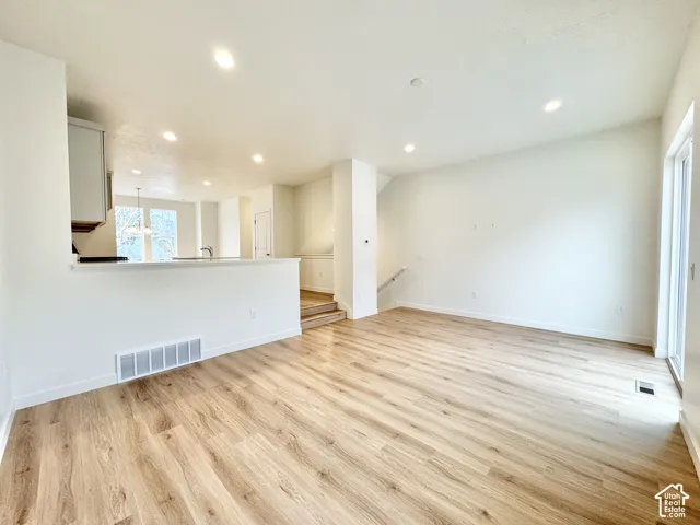 Open-concept living space featuring wood-finish flooring, recessed lighting, and a sliding glass door