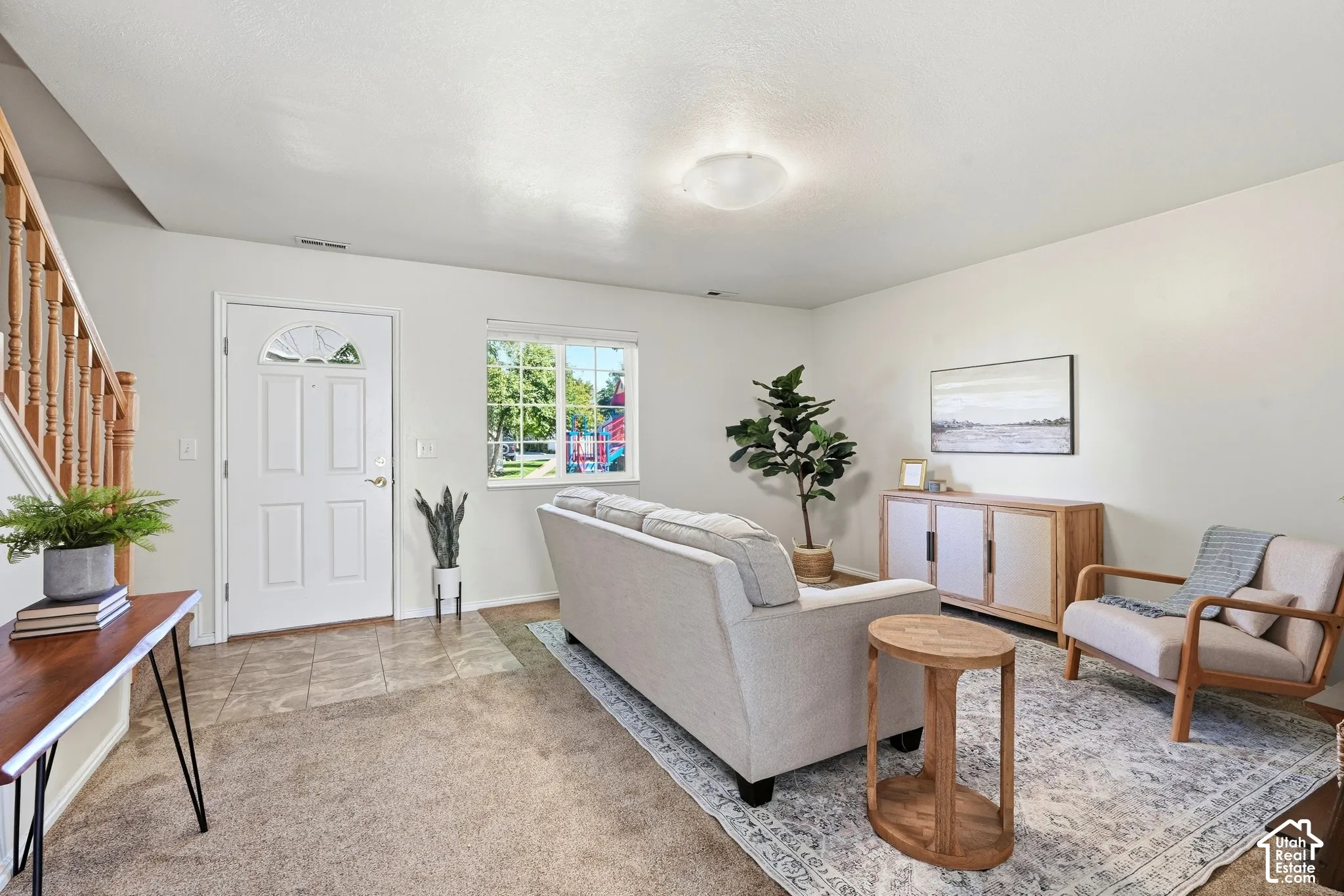 Light-filled living area featuring neutral wall tones and a combination of carpeting and tile flooring