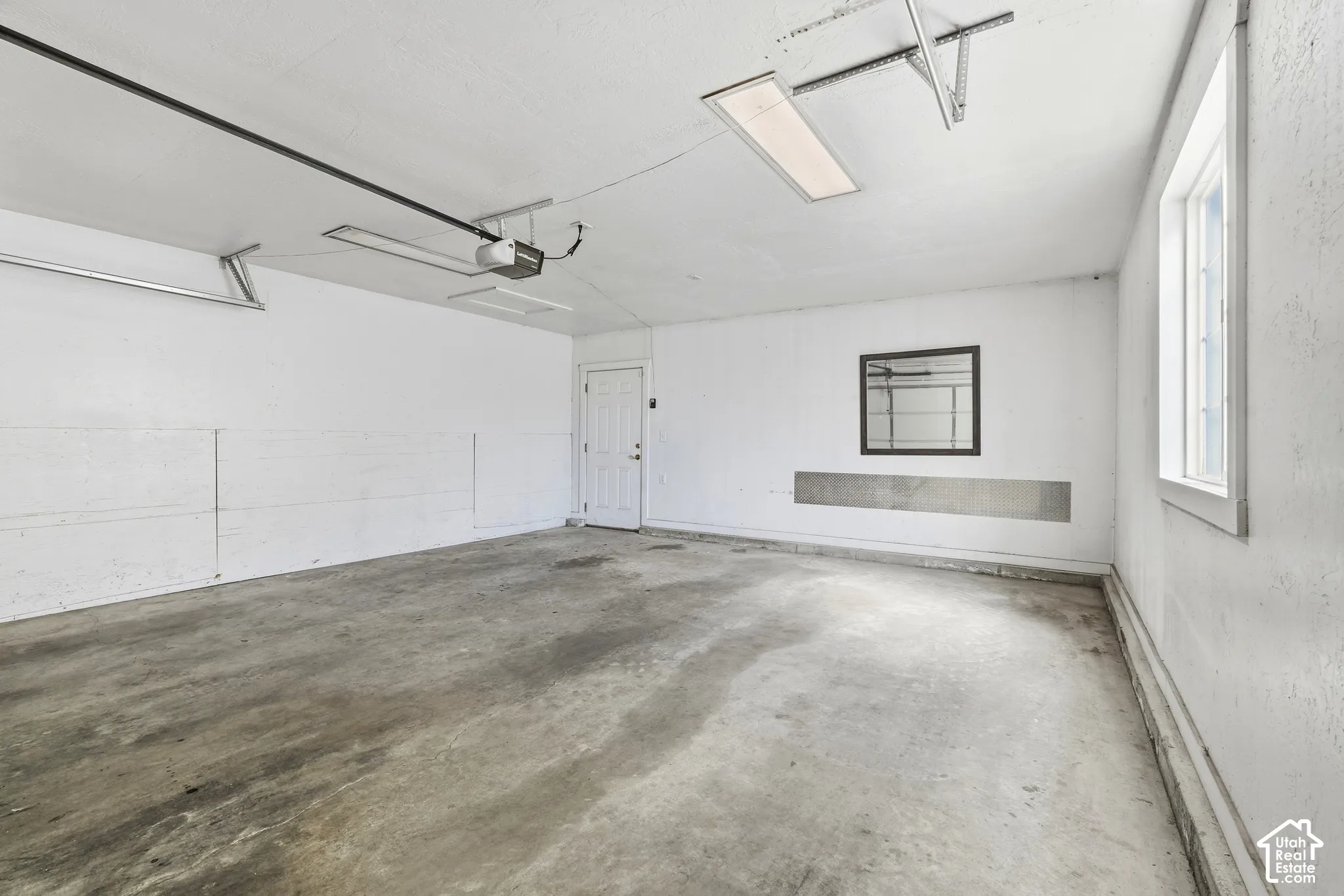 Spacious garage featuring a concrete floor, white walls, and an overhead lighting fixture