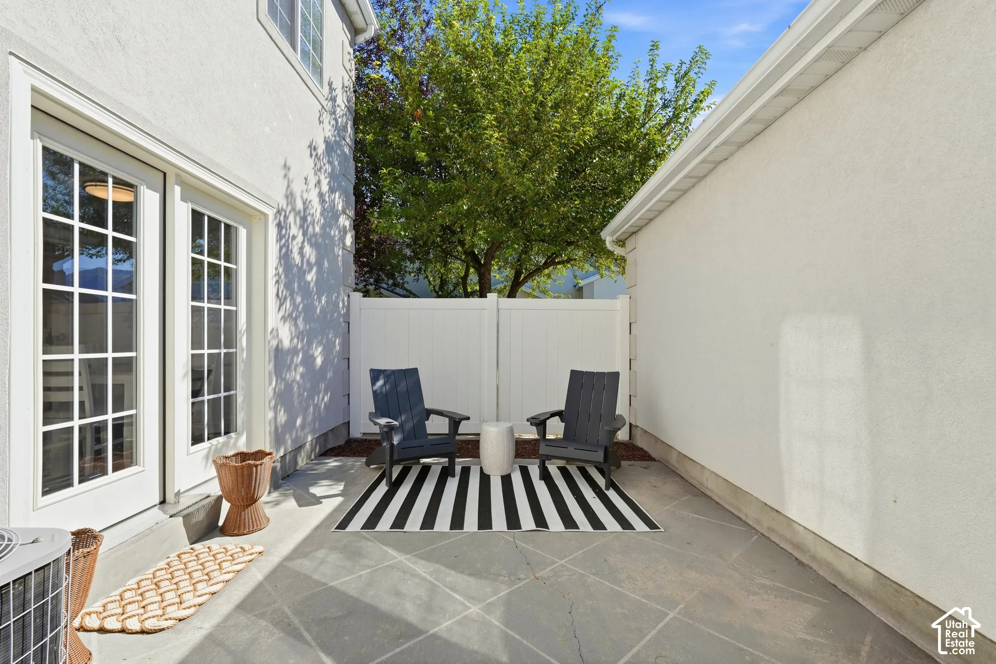 Private patio space with concrete flooring, white stucco exterior, and white privacy fencing