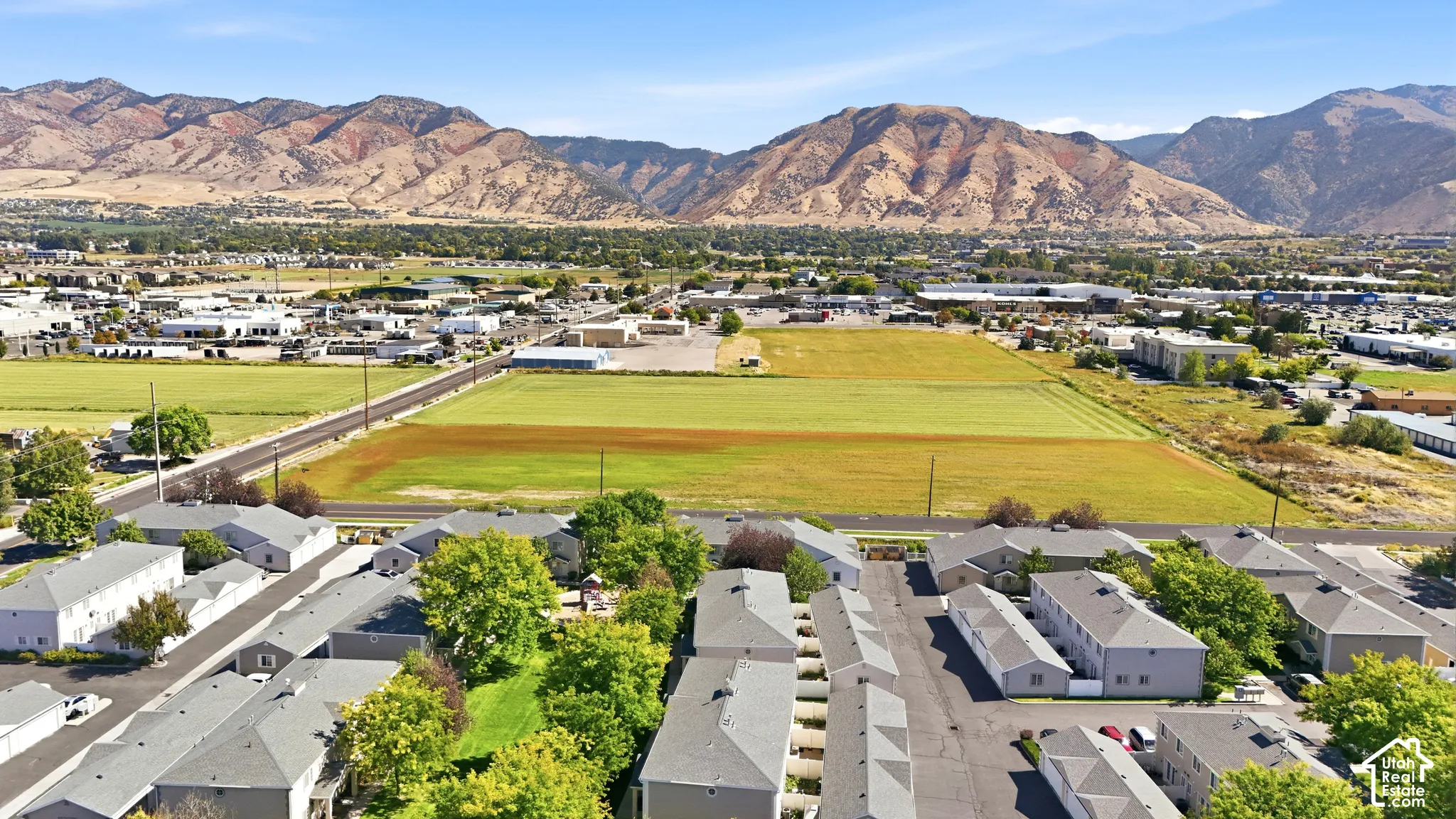 Aerial perspective featuring multi-unit properties and extensive green spaces with a mountain backdrop