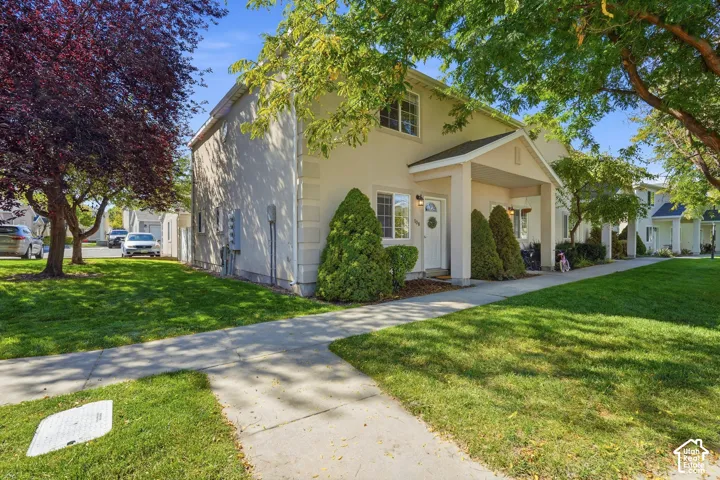 Two-story stucco exterior featuring a covered entry, mature trees, and a concrete pathway