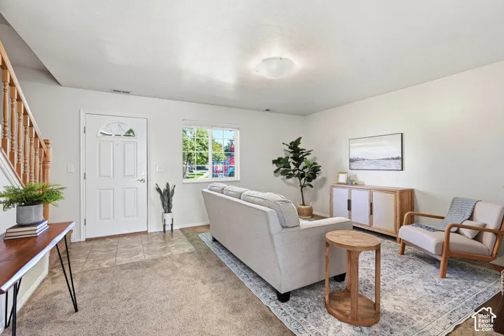 Light-filled living area featuring neutral wall tones and a combination of carpeting and tile flooring