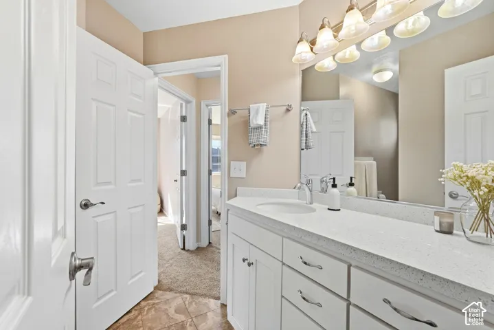 Vanity with white cabinetry, light-toned countertop, and integrated sink