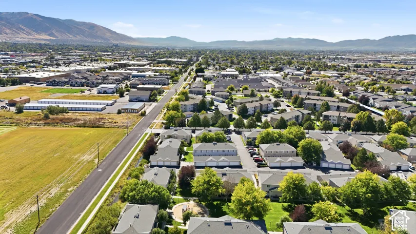 Expansive aerial perspective showcasing a residential community with mature trees, green spaces, and a paved roadway