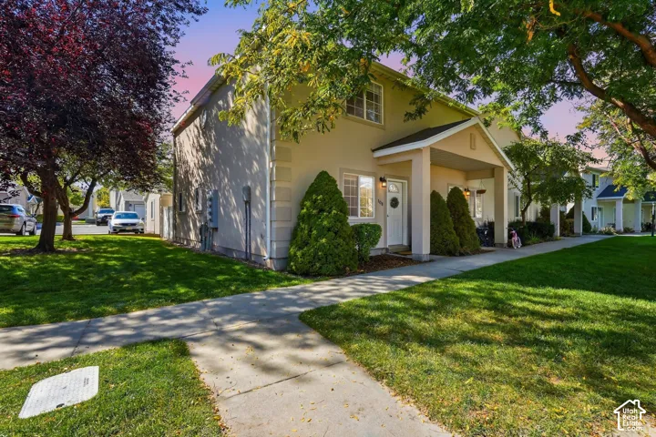 Stucco exterior with a covered entry, established landscaping, and a concrete pathway