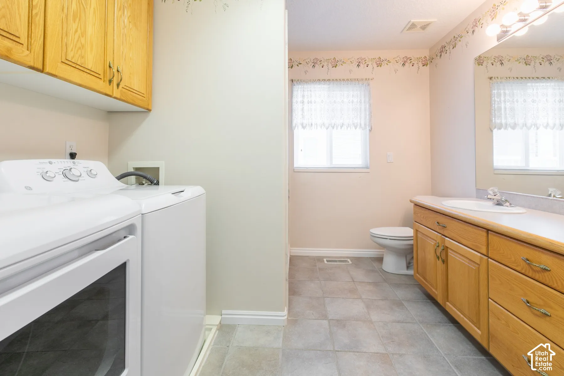Laundry area featuring wood cabinetry, tiled flooring, a built-in vanity with a sink, and a wall-to-wall mirror