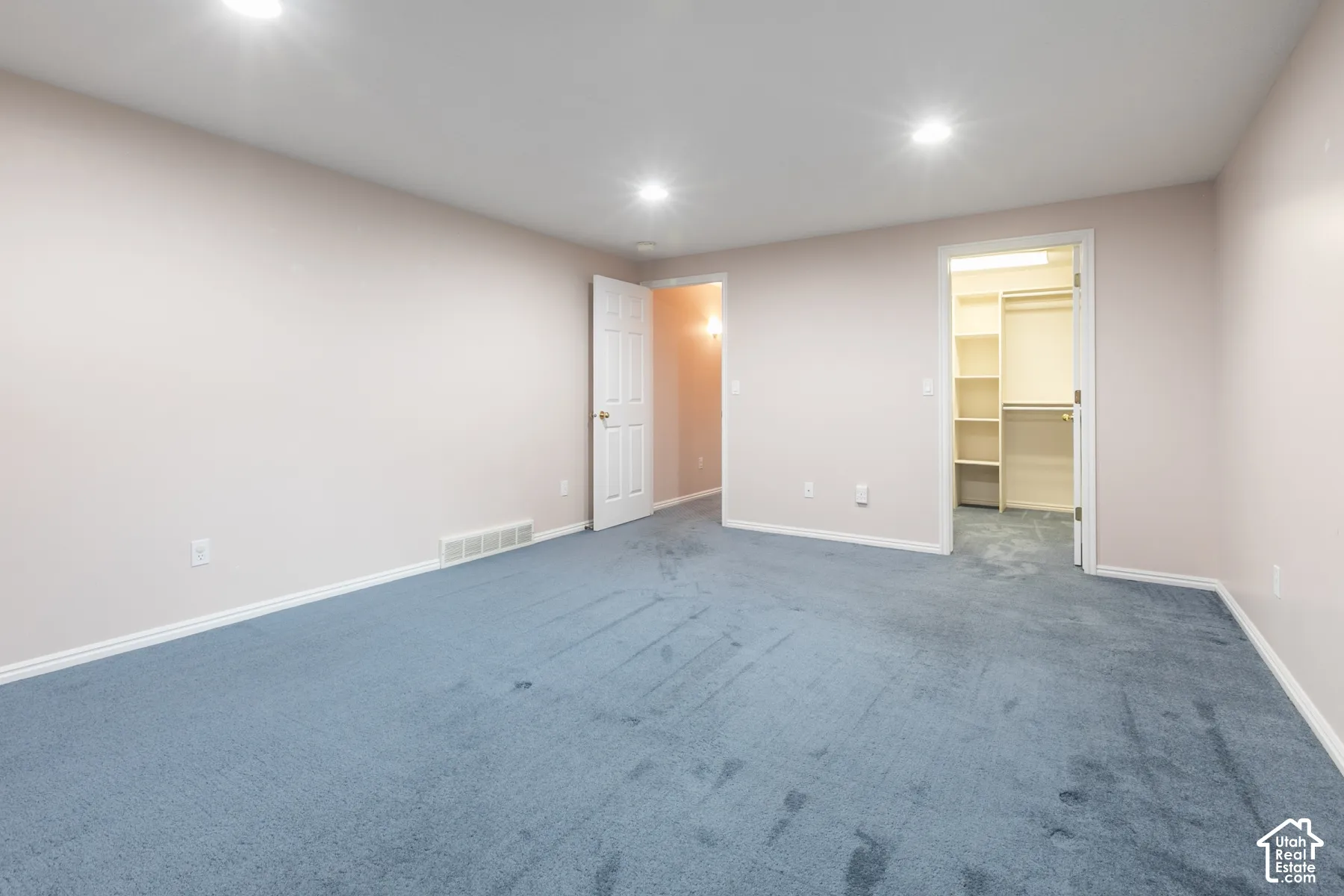 Neutral-toned interior space featuring recessed ceiling lighting, wall-to-wall carpeting, and a walk-in closet with built-in shelving