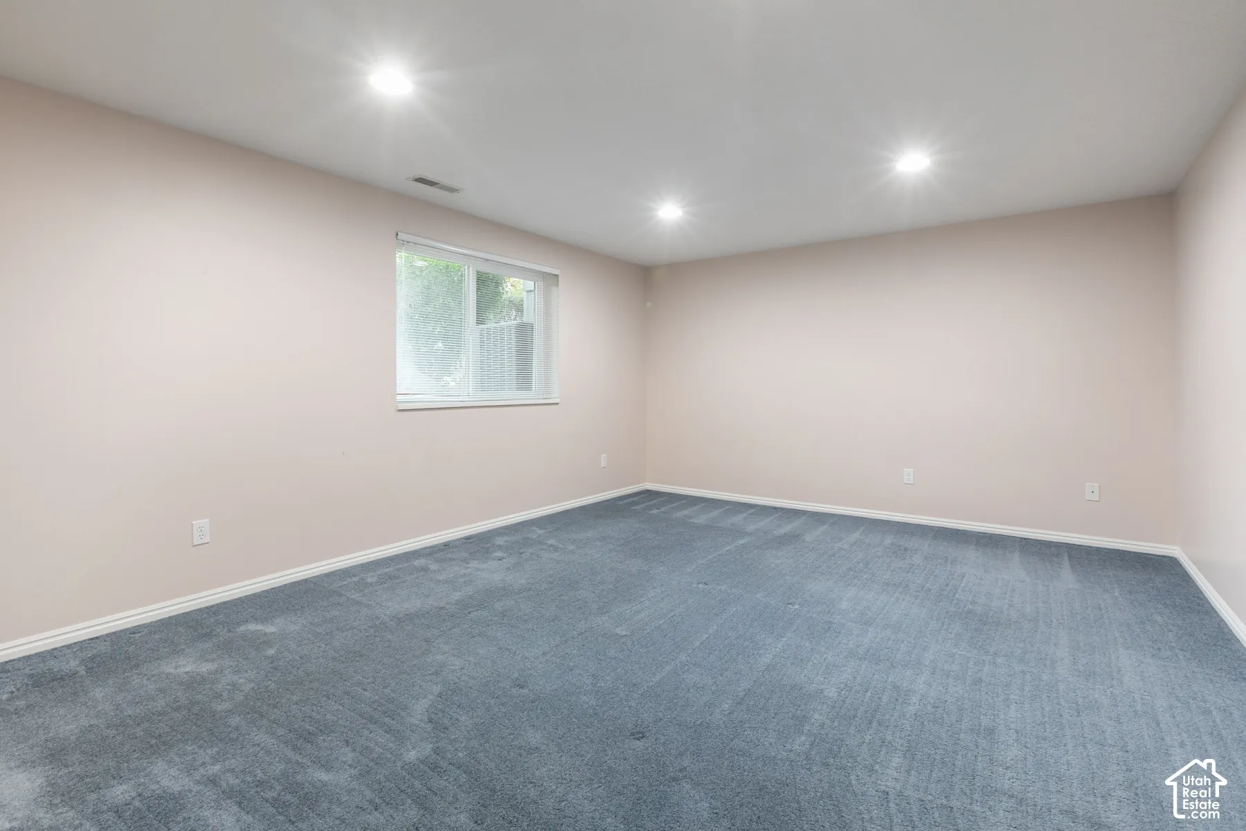 Neutral-toned interior space featuring recessed ceiling lighting, wall-to-wall carpeting, and a single-pane sliding window