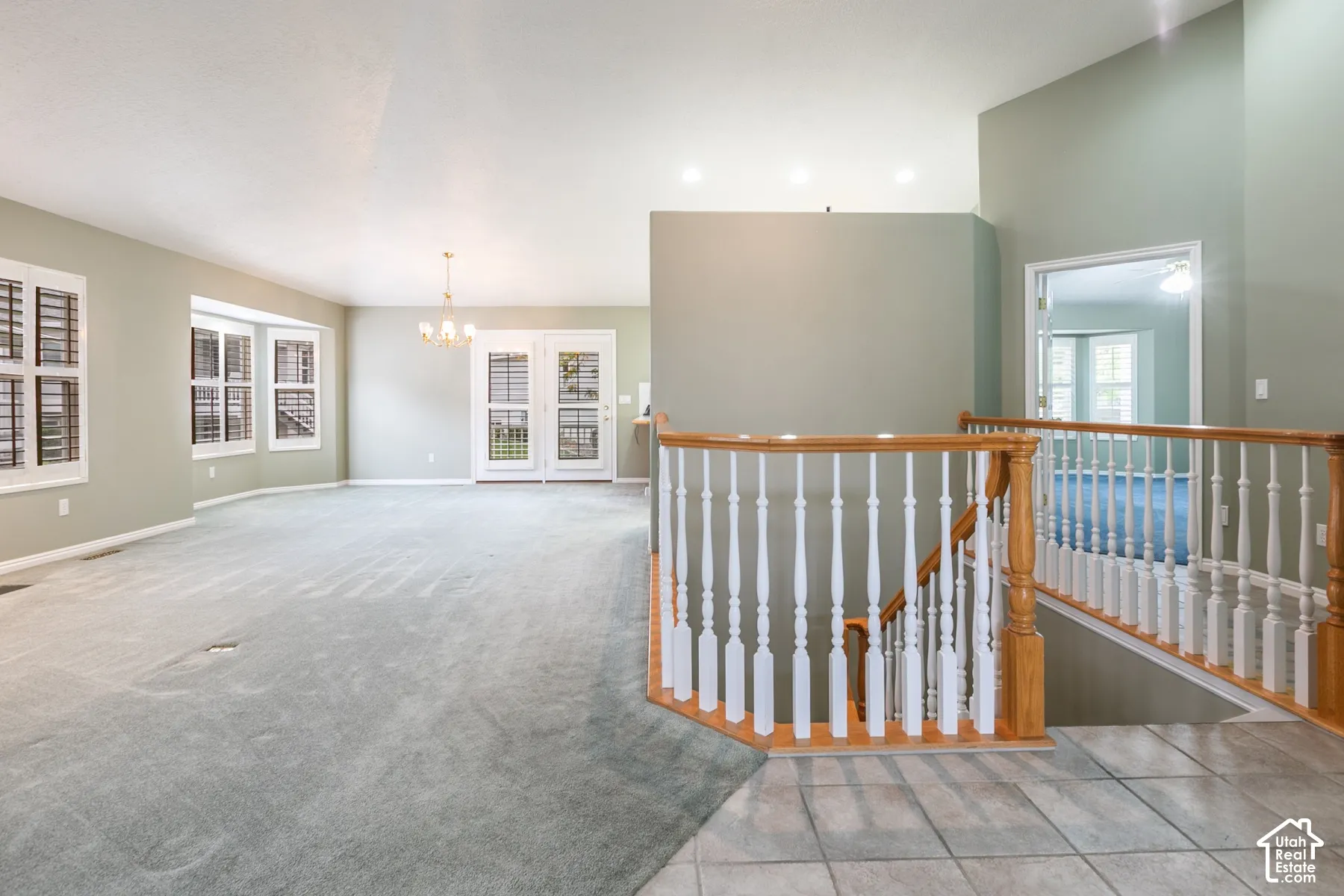Open floor plan featuring a staircase with wood handrails and white balusters, recessed lighting, multi-pane glass doors, and window shutters