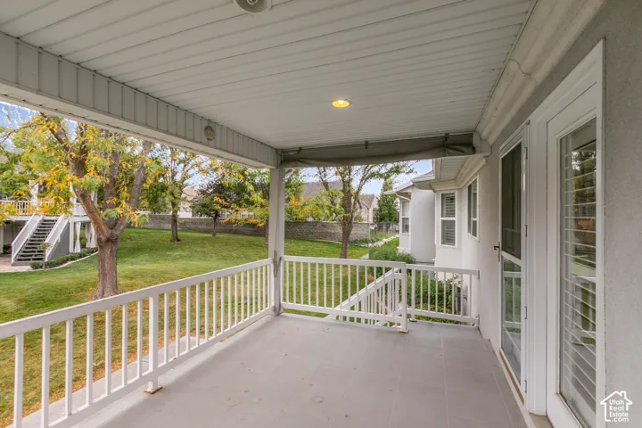 Covered patio featuring a concrete floor, white railings, recessed lighting, and a screen door