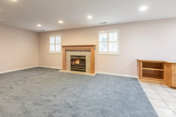 Fireplace with wood mantle and tile surround, recessed lighting, plantation shutters, and built-in wood cabinetry