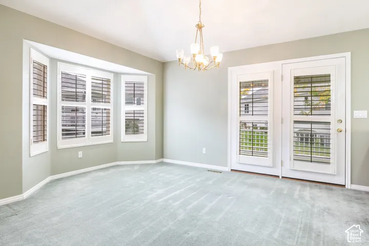 Bay window featuring plantation shutters, multi-light chandelier, and dual glass-paneled exterior doors with integrated shutter blinds